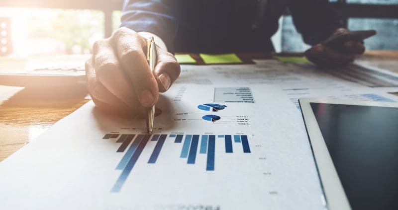a person writing on financial reports