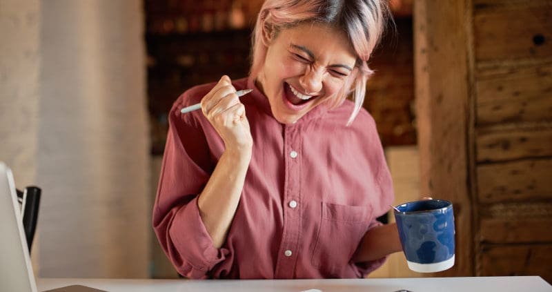 a woman celebrating with a cup of coffee