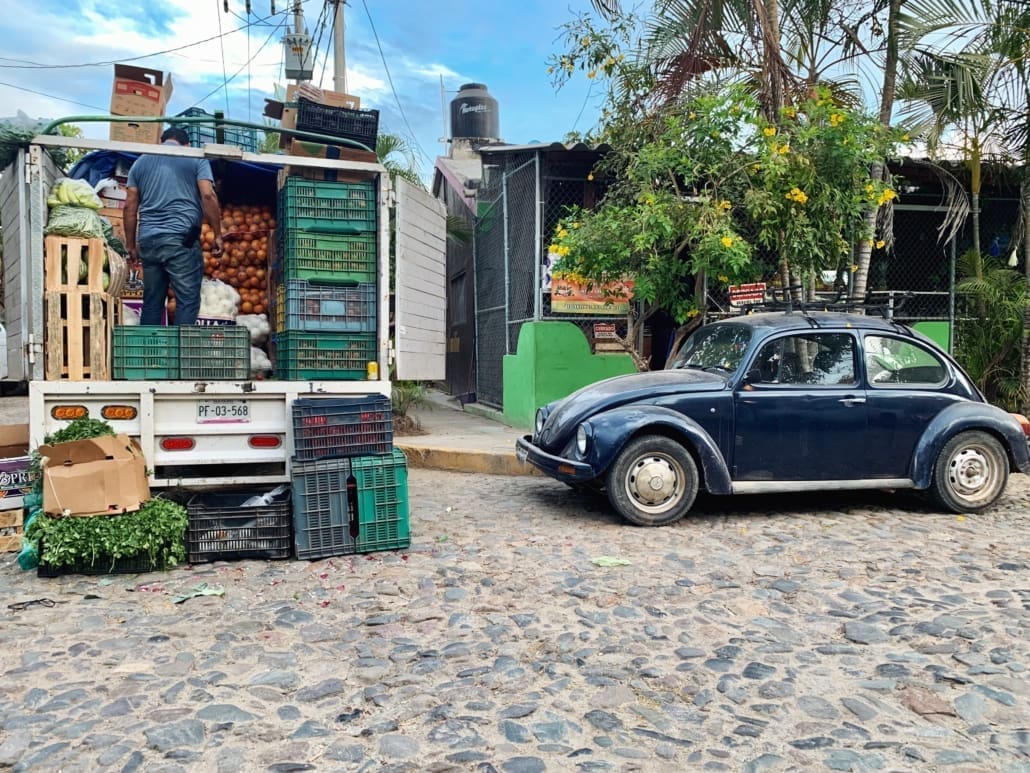 Produce delivered to market with classic vw bug on cobble stone street in front