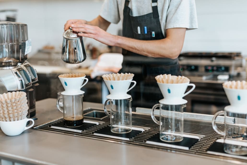 A server pours coffee into mugs.