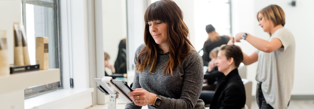 A salon owner checks her profit marginson a tablet