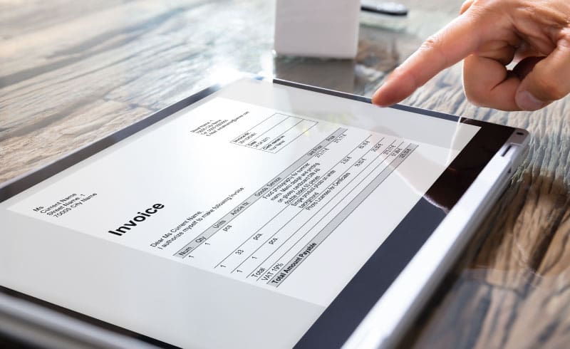 a hand pointing at a tablet with an invoice on the screen
