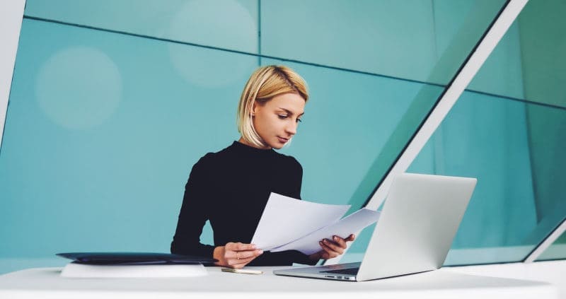 a woman looking at papers while sitting at a desk