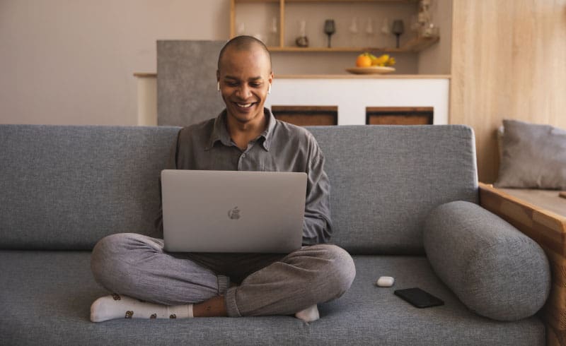 a person sitting on a couch while working on a laptop