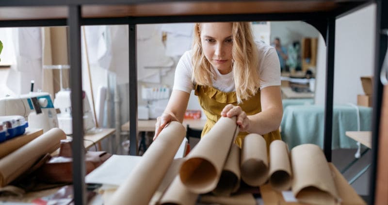 a designer looks at rolls of paper