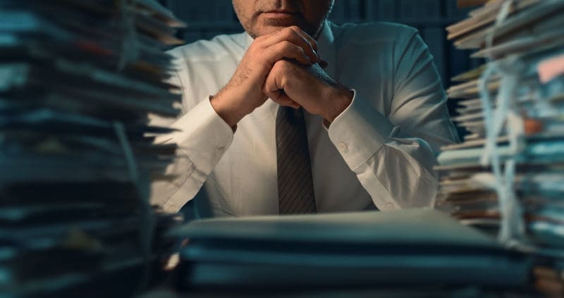 a person sitting in front of stacks of paper