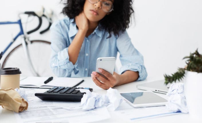 a self-employed person looking at a phone and doing taxes