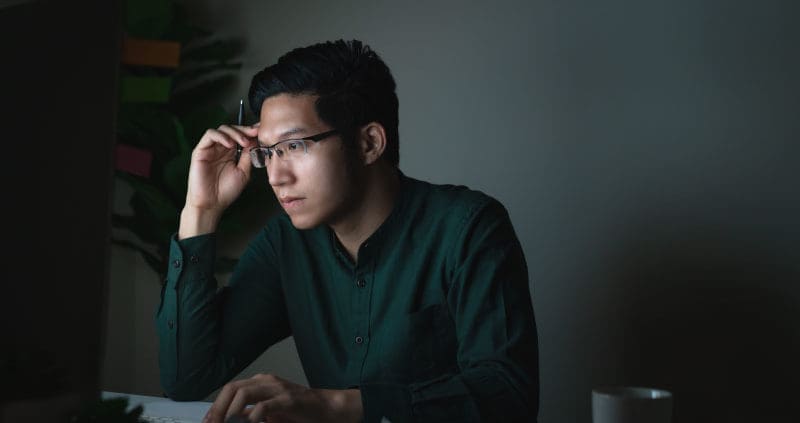 a person looking at a computer in a dark room
