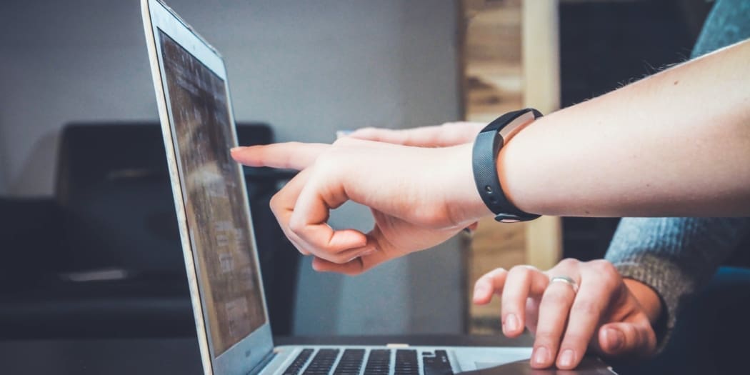 two hands pointing at a computer screen