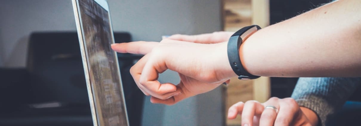 two hands pointing at a computer screen