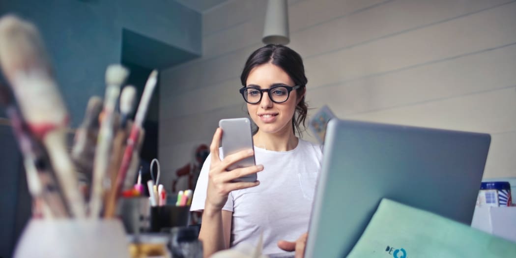 A painter looks at her phone and laptop
