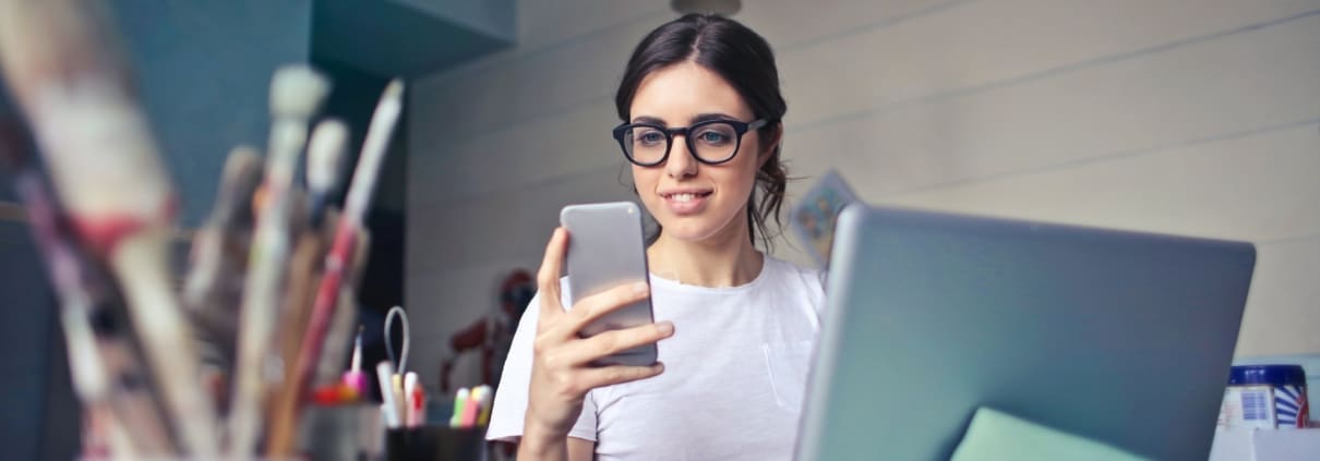 A painter looks at her phone and laptop