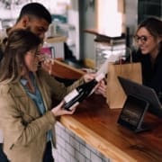 A restaurant worker helps two customers purchase wine