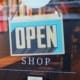 A retail shop displays an open sign in their window.
