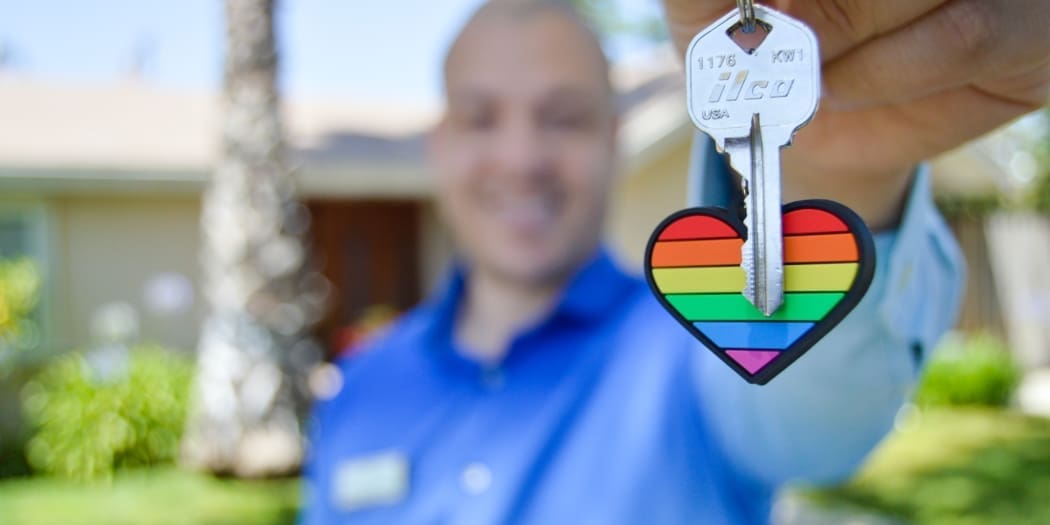 A real estate agent holds out the key for his buyer's new home.