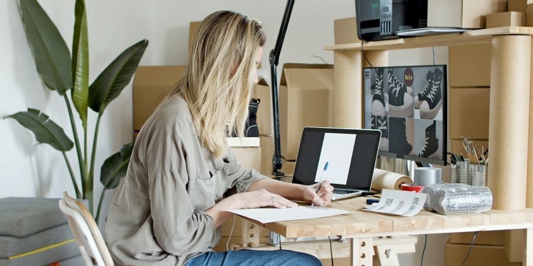 A woman writing and looking at images of shoes