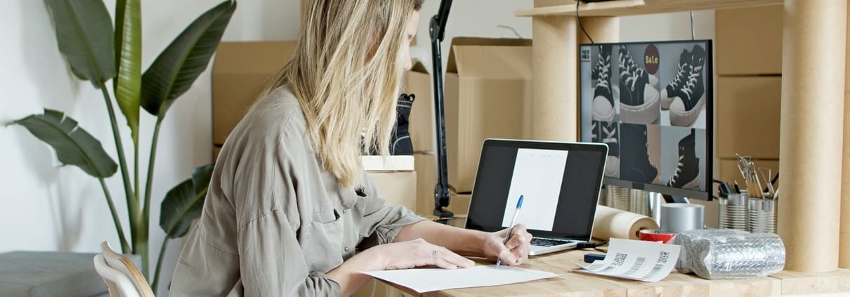 A woman writing and looking at images of shoes