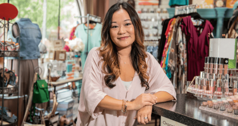A female small business owner smiles inside her boutique shop