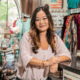 A female small business owner smiles inside her boutique shop