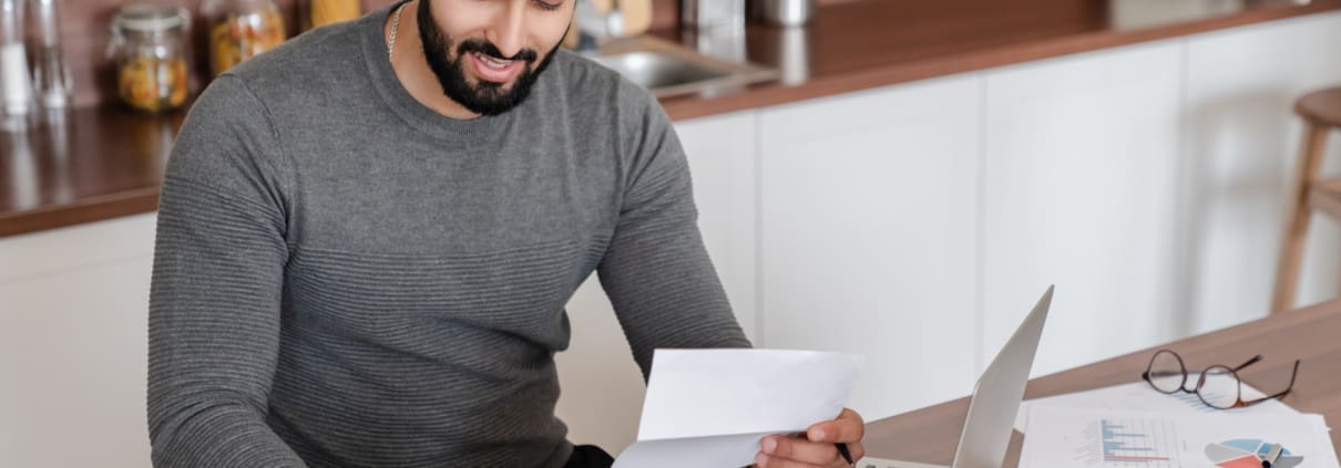 A business owner working with a laptop and calculator to determine his tax savings