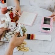 Two people counting money and writing amounts on paper