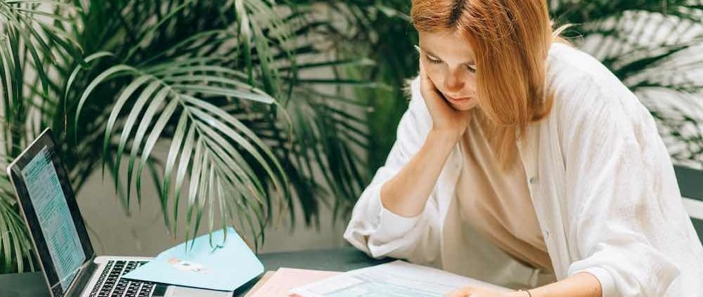 a woman sitting in front of plants and looking at papers