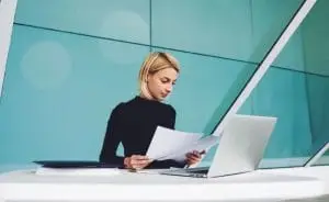 a woman looking at papers while sitting at a desk