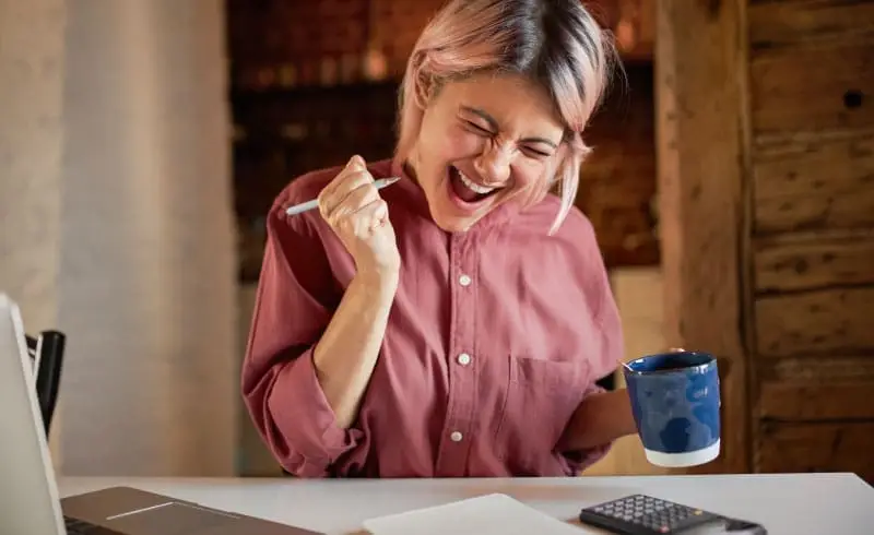 a woman celebrating with a cup of coffee