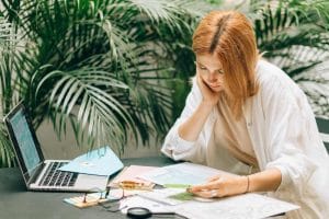 a woman sitting in front of plants and looking at papers
