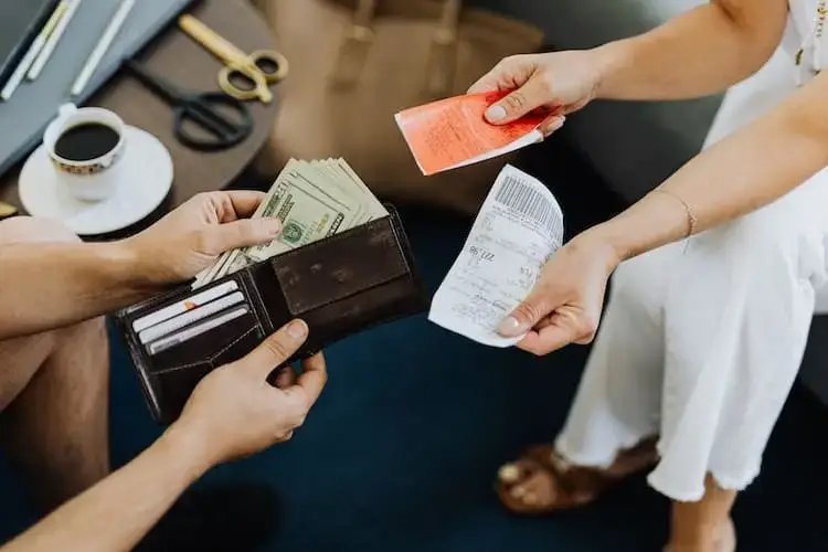 Two people exchanging receipts and money