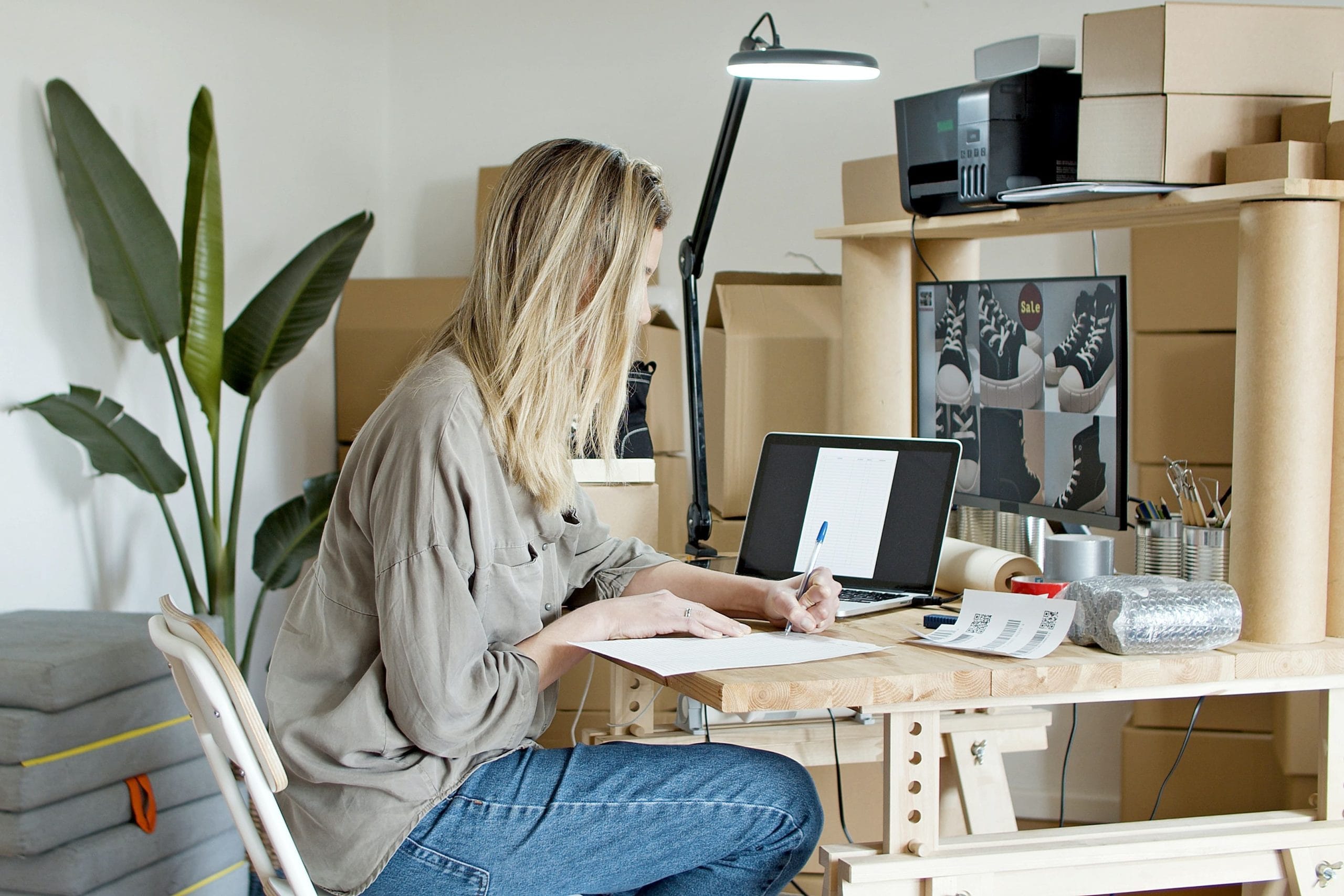 A woman writing and looking at images of shoes