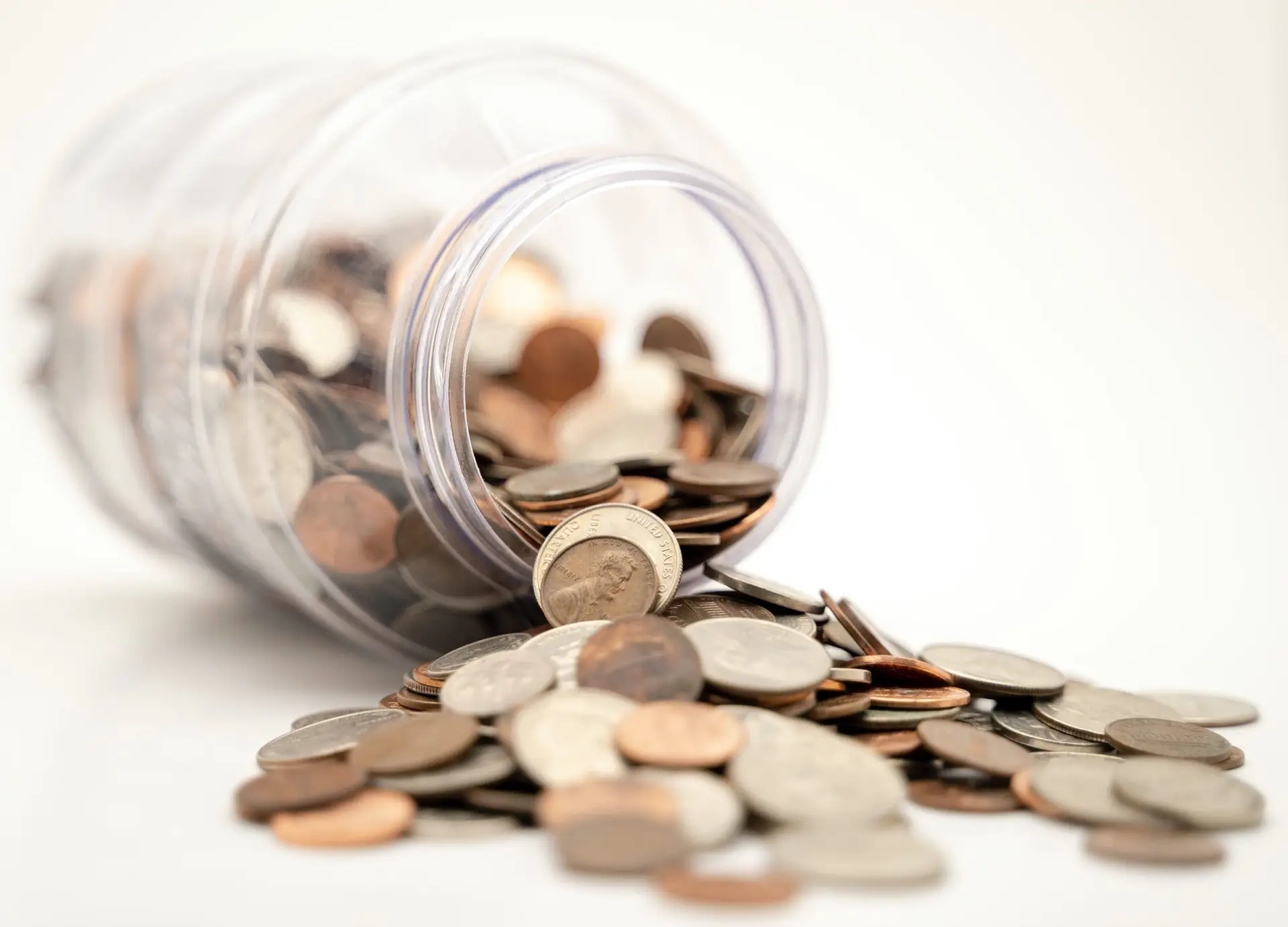Coins spills out of a glass jar on a table