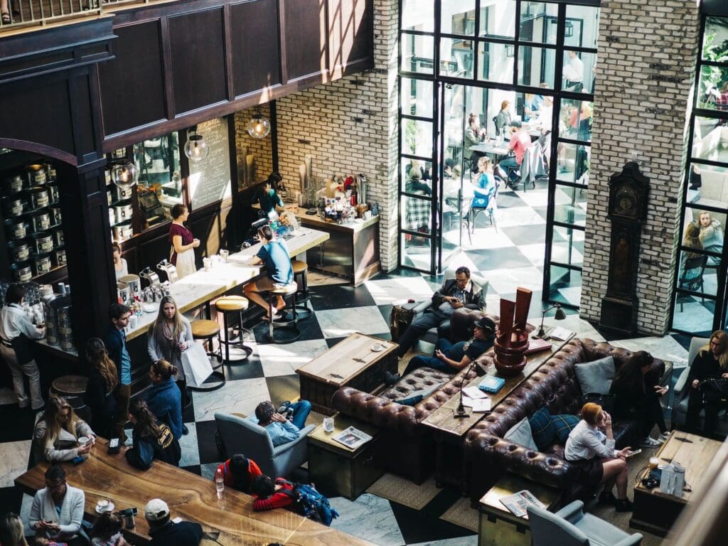 A restaurant with patrons|An employee hads a customer their food order.