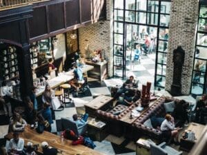 A restaurant with patrons|An employee hads a customer their food order.