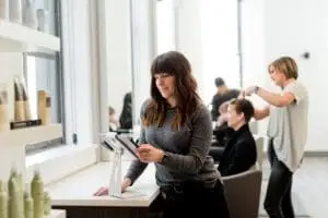 A salon owner checks her profit marginson a tablet