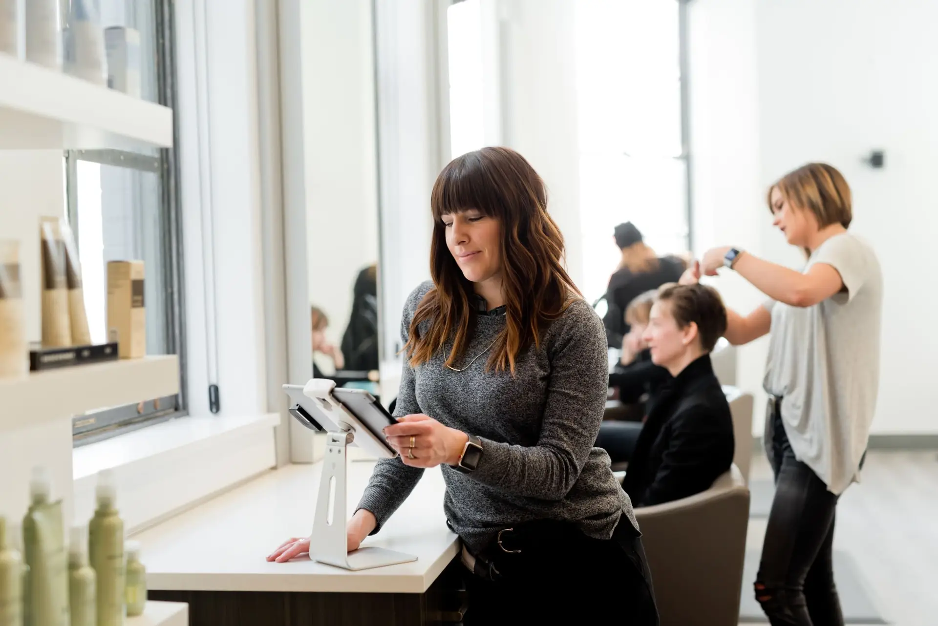 A salon owner checks her profit marginson a tablet