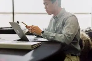 A man in an oxford shirt looks at his bookkeeping on his laptop