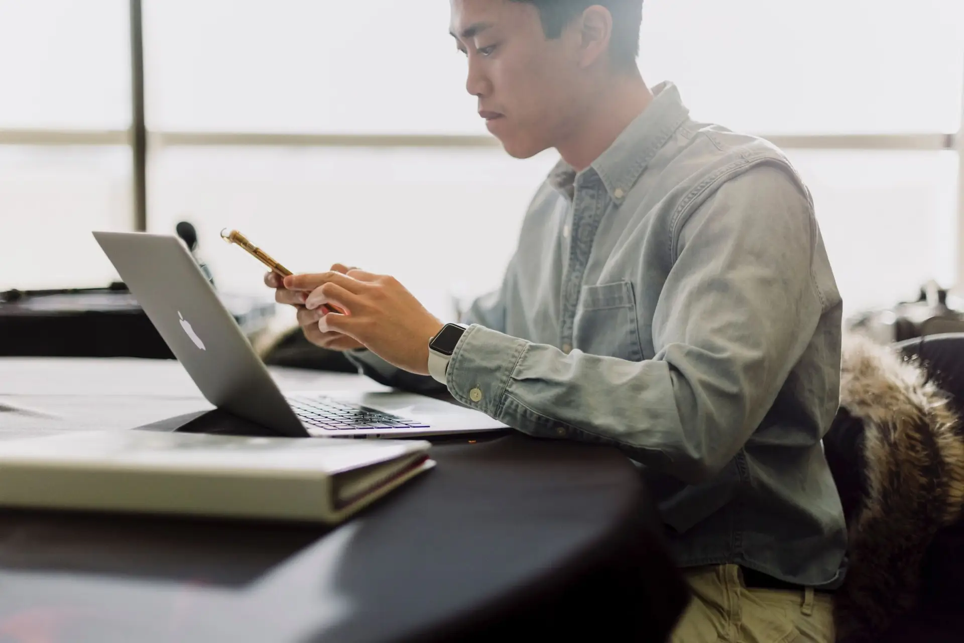 A man in an oxford shirt looks at his bookkeeping on his laptop